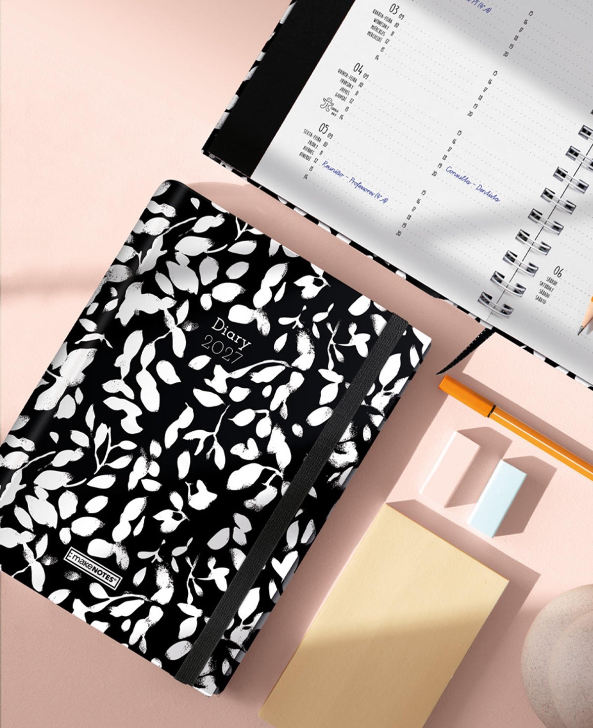 Agenda semanal A5 2027 com capa preta e padrão de folhas, vista inclinada