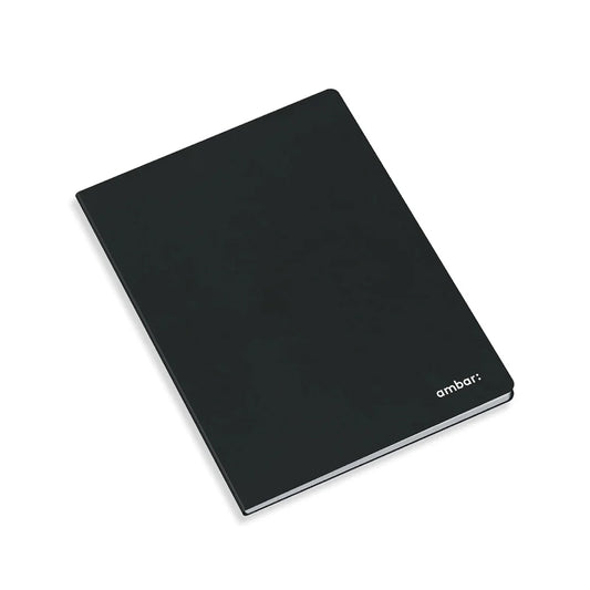 Caderno agrafado Ambar A4 de capa preta, aberto exibindo folhas brancas lisas sem pauta, design minimalista para desenho e escrita livre.