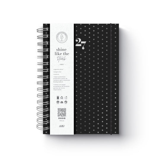 Agenda diária de 2027 Eco Skye da Firmo, em preto com padrão de pequenas estrelas prateadas, encadernação em espiral e uma faixa protetora branca com o texto "shine like the stars", sobre fundo neutro.