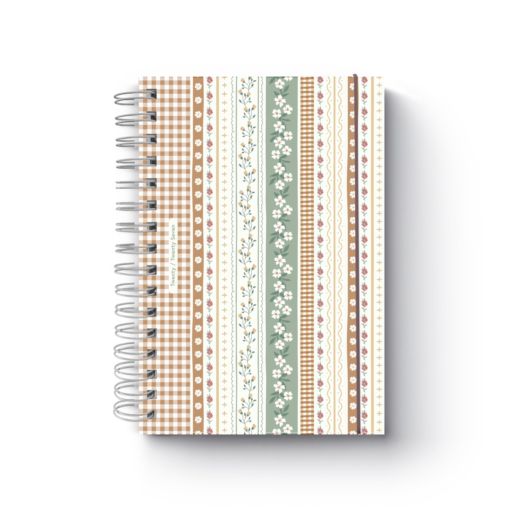 Agenda diária de 2027 Nola da Firmo com capa de padrão ilustrado estilo patchwork floral e axadrezado castanho, encadernação em espiral e elástico de fecho, sobre fundo branco.