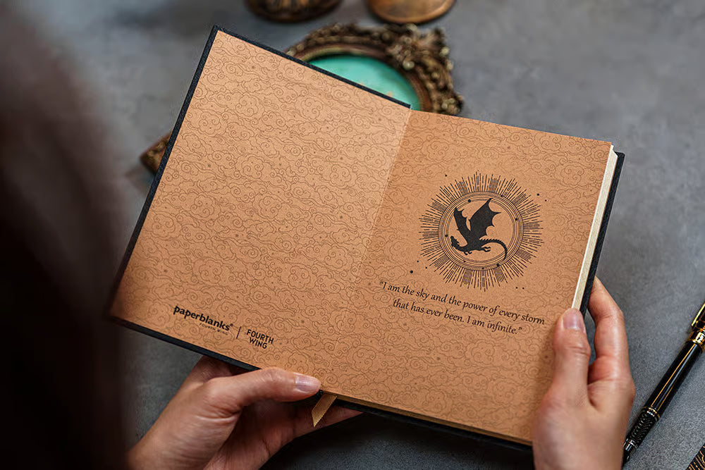 Agenda com capa traseira bege, padrão ornamental e emblema dourado central