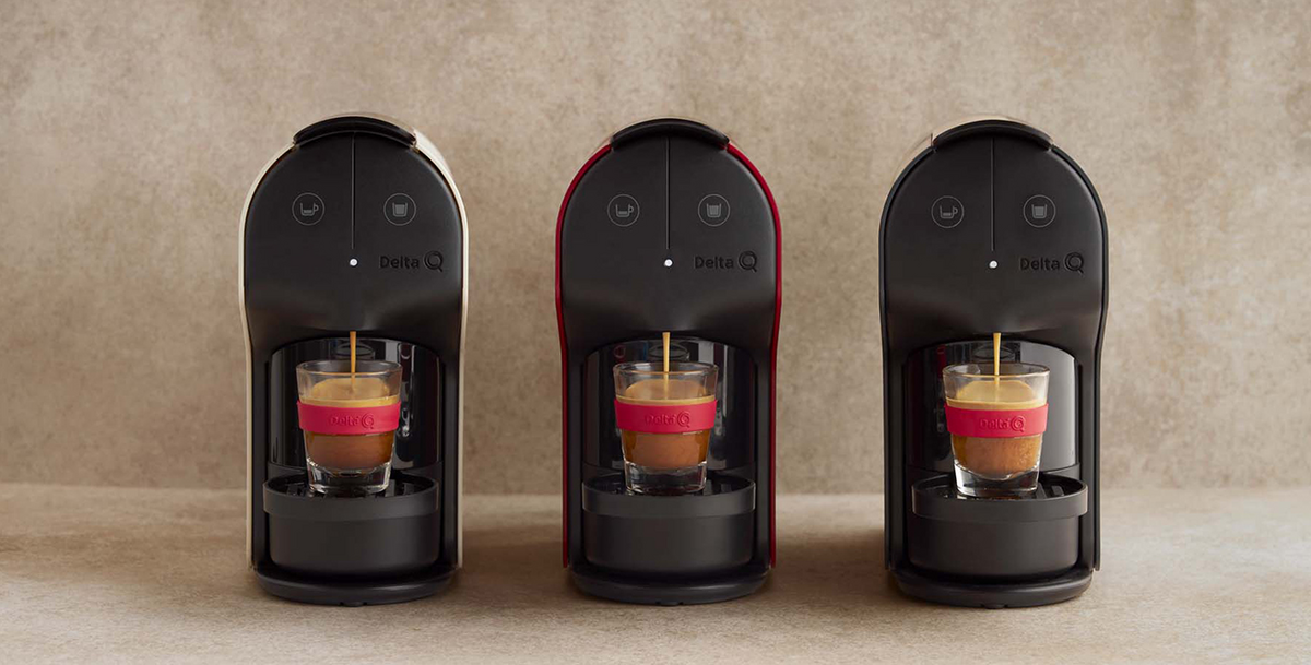 Três máquinas de café de cápsulas Delta Q Quick, em cores preto, vermelho e branco